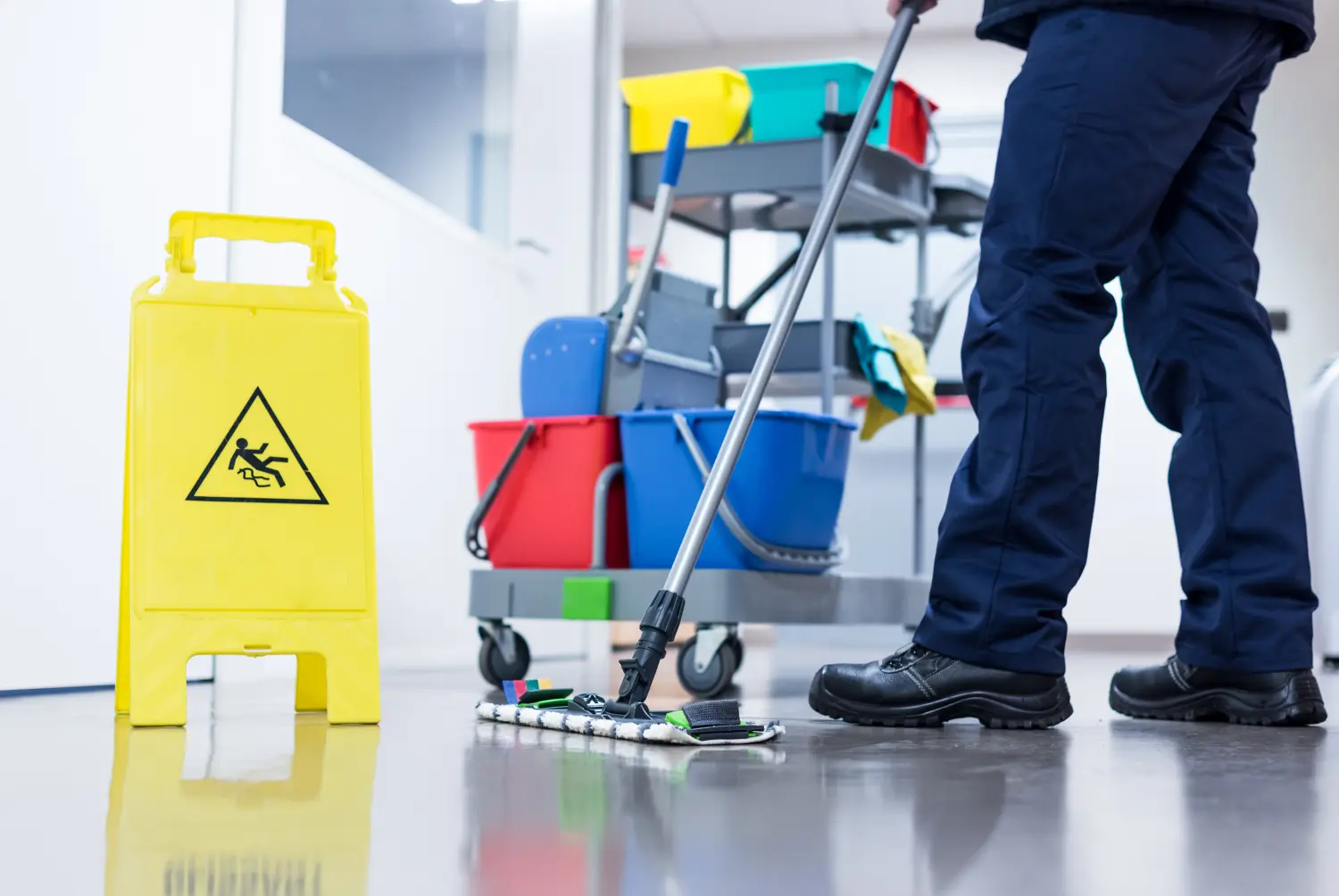 Hausmeister wischt den Boden im Büro mit einem Wagen